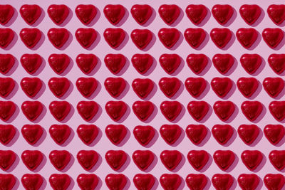 Heart-shaped candy on pink background
