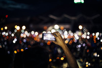 Low angle view of hand holding illuminated smart phone at night