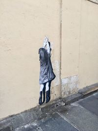 Woman walking on footpath against wall