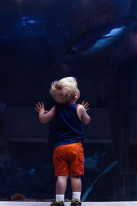 Rear view of boy standing against wall