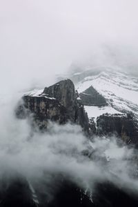 Scenic view of snow covered mountain surrounded by low-hanging clouds 