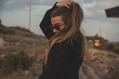 Portrait of young woman standing against sky during sunset