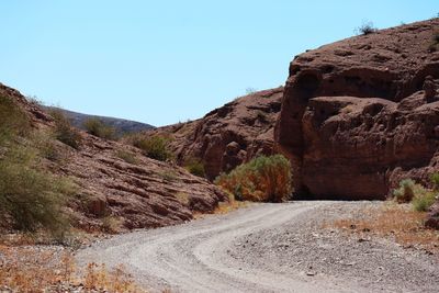 Road by mountain against clear blue sky