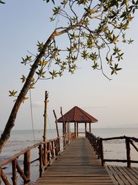 Wooden pier on sea against clear sky