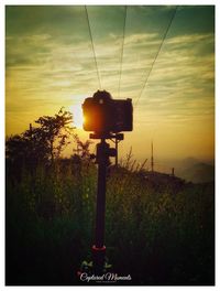 Silhouette camera against sky during sunset