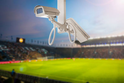 Close-up of security camera at soccer field against sky