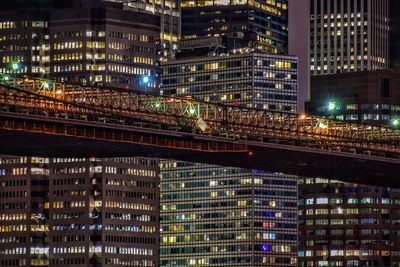 Brooklyn bridge against illuminated buildings in city at night