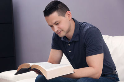 Side view of young man sitting on book