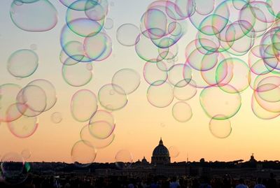 View of bubbles against buildings at sunset