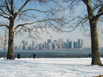 Cityscape by river against sky during winter