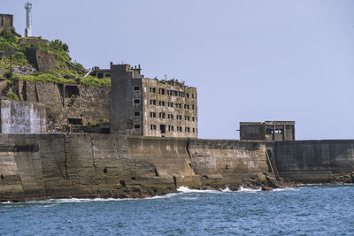 Old building by sea against clear sky