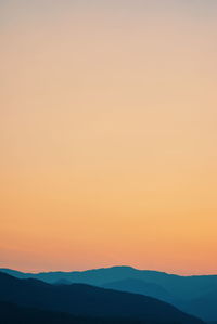 Scenic view of silhouette mountain against orange sky during sunset