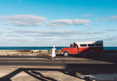 Cars on road by sea against sky