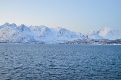 Scenic view of sea and snowcapped mountains against clear sky