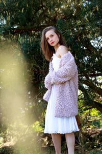 Young woman standing by tree against plants