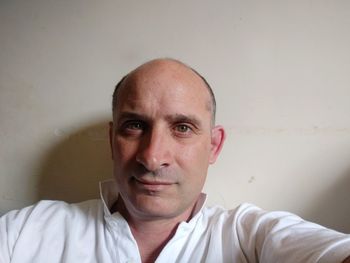 Close-up portrait of balding mature man against wall at home