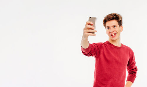 Portrait of smiling young man using smart phone against white background
