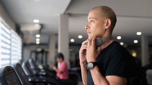 Young man looking away while standing in gym