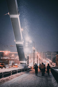 People walking on illuminated street at night