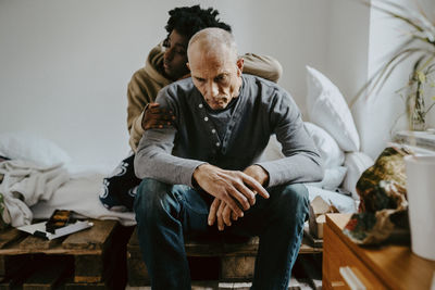 Daughter consoling father while sitting in bedroom