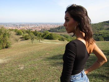 Side view of young woman standing on land against sky