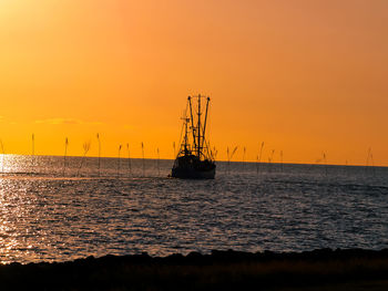 Silhouette ship in sea against sky during sunset