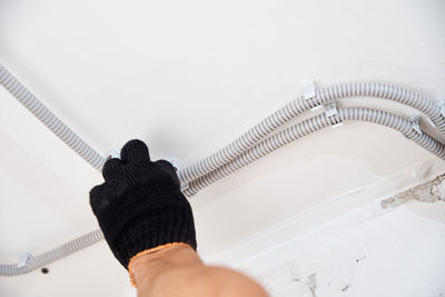 Midsection of person holding umbrella against white wall