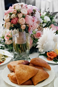 Festive table with a bouquet of roses in a vase and a plate of pies.