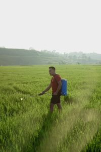 Rear view of man standing on field against clear sky