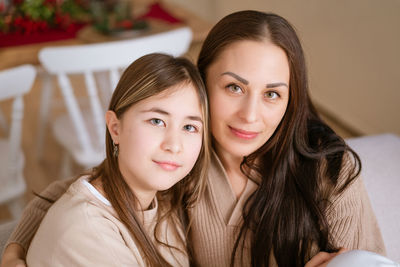 Mom and daughter sitting on couch cuddled together waiting for christmas