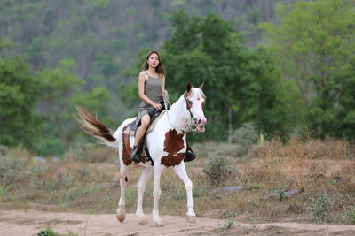 Full length of teenage girl riding horse on land