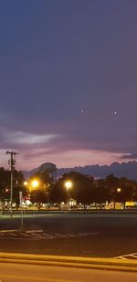 Illuminated street against sky at night