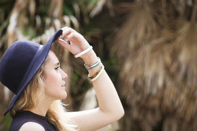 Woman holding sun hat while looking away outdoors