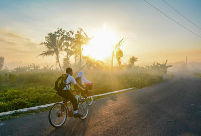 People riding bicycle on road against sky