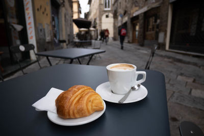 True italian breakfast, cappuccino coffee and a brioche on the street