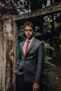 Portrait of young man standing against wall