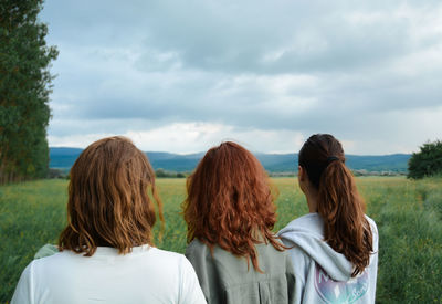 Rear view of woman with arms raised against sky