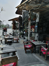 Empty chairs and tables at sidewalk cafe by building