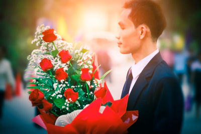 Side view of mid adult man holding bouquet