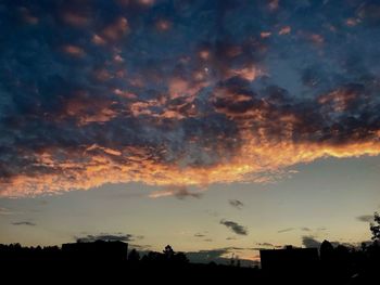Low angle view of silhouette trees against dramatic sky