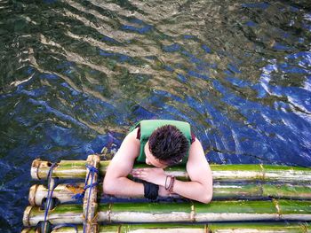 Man standing by wooden raft in lake