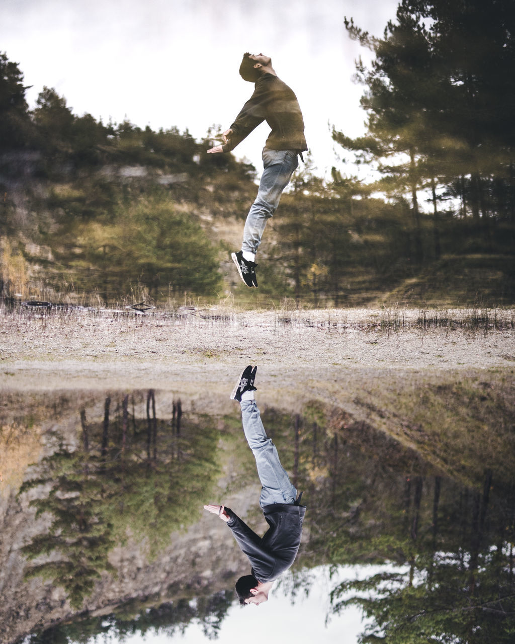 LOW ANGLE VIEW OF MAN JUMPING AGAINST TREE