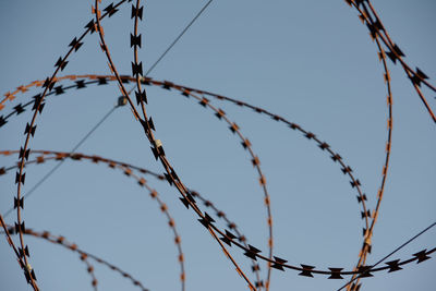 Low angle view of barbed wire against sky