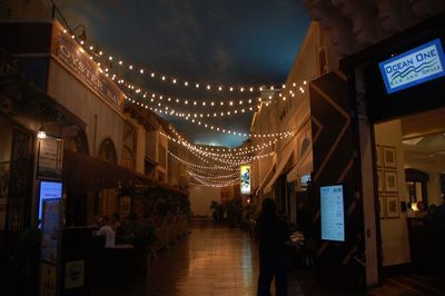 Illuminated street amidst buildings at night