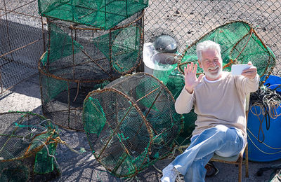 Portrait of man doing video call while sitting against fishing net