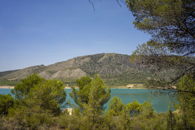 Scenic view of lake and mountains against clear blue sky