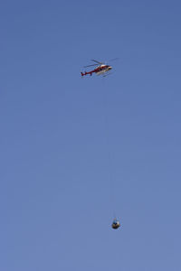 Low angle view of helicopter flying against clear blue sky