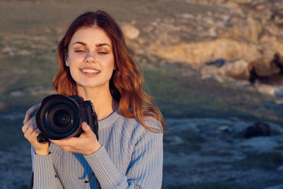 Portrait of smiling young woman holding camera