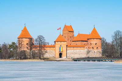 Medieval castle of trakai, vilnius, lithuania in winter, with frozen lake and ukrainian flag