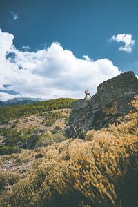 Man climbing rock on landscape against sky